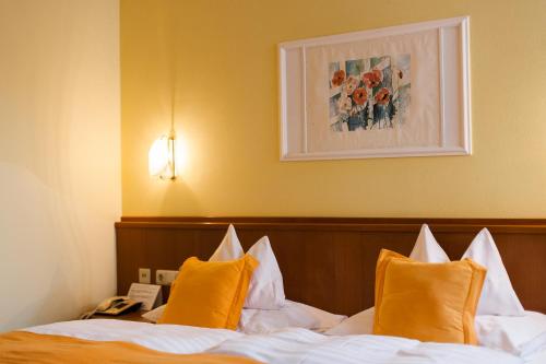 Habitación de hotel con cama con almohadas de color naranja en Hotel Schilcherlandhof, en Stainz