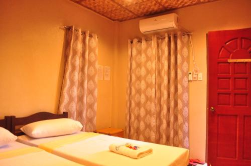 a bedroom with two beds and a red door at Ceazar's Place in Dauin