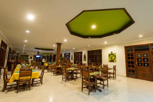 a restaurant with tables and chairs and a large green screen at Arusha Planet Lodge in Arusha