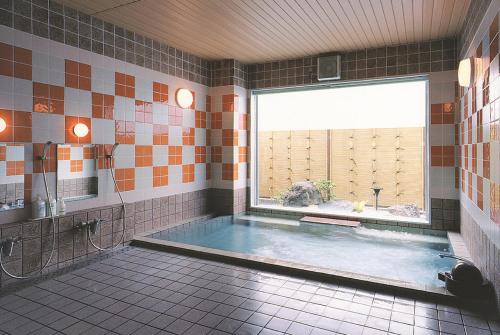 a bathroom with a large tub with a large window at Hotel Route-Inn Sapporo Shiroishi in Sapporo