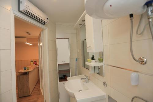 a white bathroom with a sink and a mirror at Apartment Centar in Pula