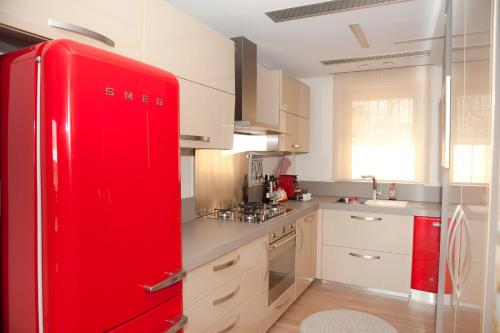 a red refrigerator in a kitchen with white cabinets at Unique Acropolis View in Athens