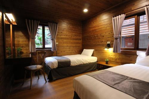 two beds in a room with wooden walls and windows at Taichung Business Hotel - Immortals Hills in Heping