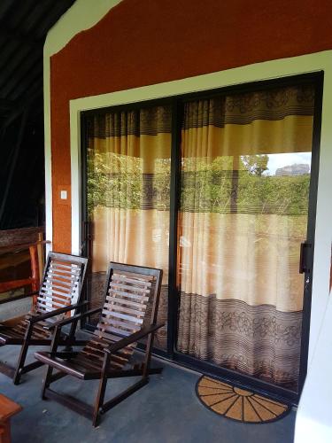 two chairs sitting on a porch with a large window at Sigiri Heritage Villa in Sigiriya