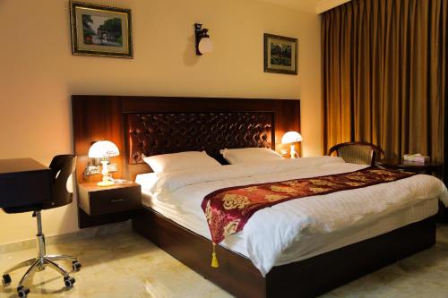 a bedroom with a large bed and a desk with two lamps at Qaser Al-Sultan Hotel Suites in Amman