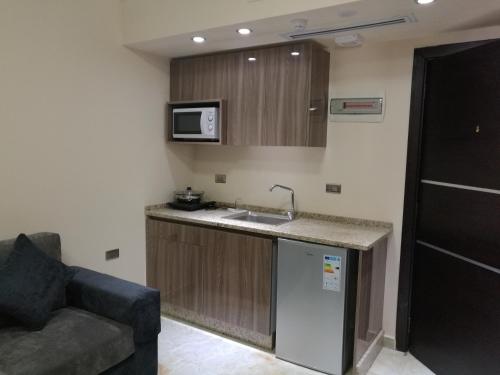 uma cozinha com um lavatório e um sofá num quarto em Qaser Al-Sultan Hotel Suites em Amã
