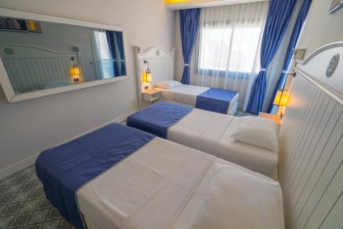 a hotel room with two beds and a mirror at Marmaris Beach Hotel in Marmaris