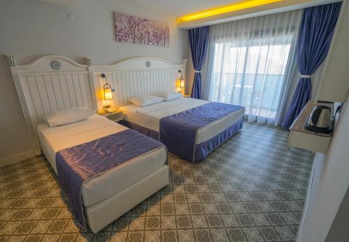 a hotel room with two beds and a window at Marmaris Beach Hotel in Marmaris