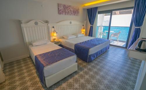 two beds in a hotel room with a view of the ocean at Marmaris Beach Hotel in Marmaris