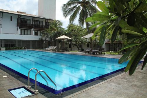 a large swimming pool next to a building at Goldi Sands Hotel in Negombo