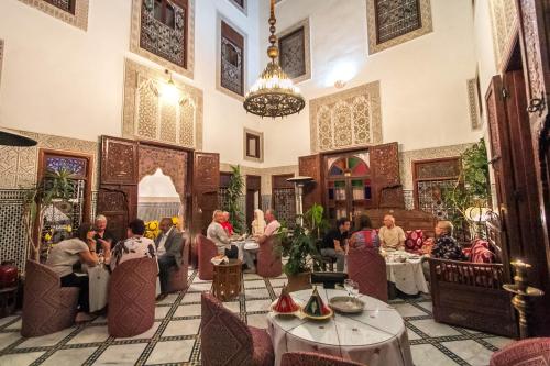 a group of people sitting at tables in a restaurant at Riad Dar Chrifa in Fez