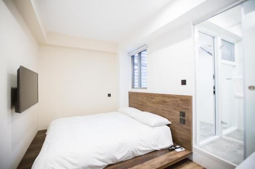 a white bedroom with a bed and a window at We Come Hostel in Taipei
