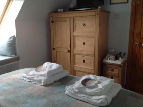 a bedroom with two towels on a bed with a dresser at Taigh Pa in Uig