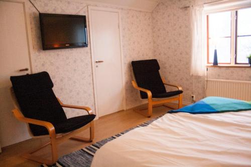 a bedroom with two chairs and a bed and a television at Pensionat Prästgården in Töreboda