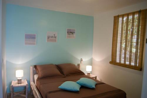 1 dormitorio con sofá marrón y 2 almohadas azules en Résidence Anamanga, en Sainte-Anne