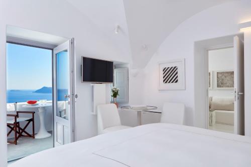 a white bedroom with a view of the ocean at Canaves Sunday in Oia