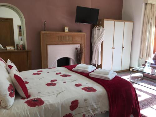 a bedroom with a bed with red flowers on it at Blackburn Villa B&B in Ayr