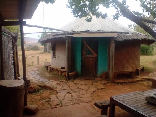 a small house with a thatched roof and a door at Joy River Backpackers in Moremela