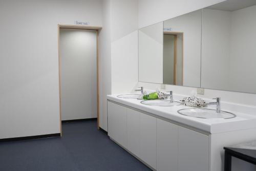 a white bathroom with two sinks and a mirror at Guesthouse Sumiyoshi in Osaka