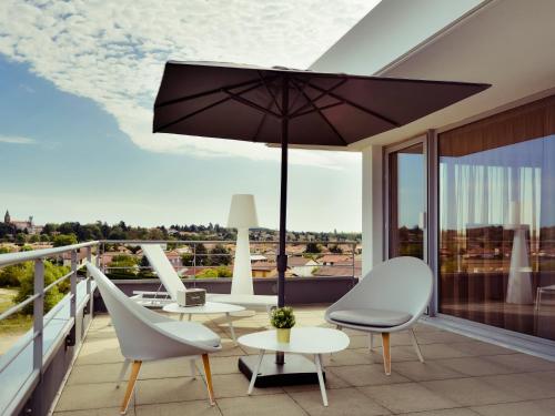 a balcony with a table and chairs and an umbrella at Mercure Lyon Genas Eurexpo in Genas
