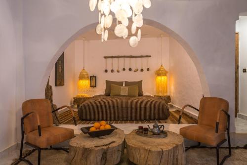 una camera da letto con un letto, due sedie e un tavolo di Munga Guesthouse a Taghazout