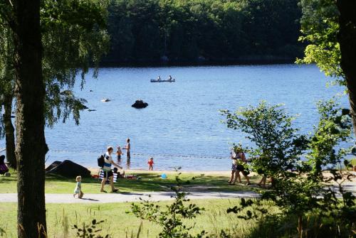 um grupo de pessoas na praia em um lago em Långasjönäs Camping & Stugby em Karlshamn