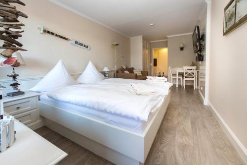 a white bedroom with a large bed with white sheets at Seewind in Sankt Peter-Ording