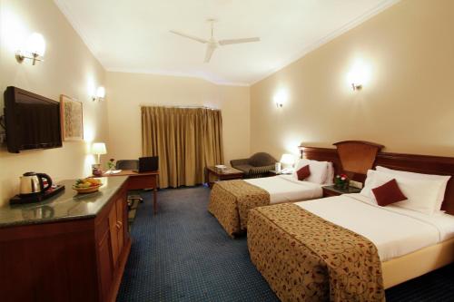 a hotel room with two beds and a television at Hotel Madhuban in Dehradun