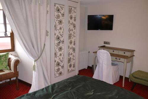 a bedroom with a bed and a desk and a television at Le Chapeau Rouge in Lusignan