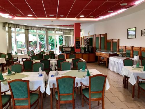 un comedor con mesas, sillas y un piano en Well Hotel, en Harkány