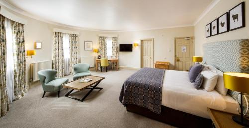 a hotel room with a bed and a table and chairs at Mercure Gloucester Bowden Hall Hotel in Gloucester