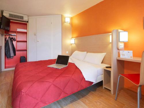 a bedroom with a red bed with a laptop on it at Premiere Classe Villepinte Centre - Parc des Expositions in Villepinte