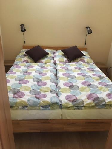 a bed with a colorful comforter and two pillows at PENZION HNAČOV in Zavlekov