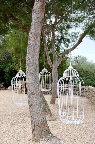 two white bird cages hanging from a tree at Finca Hotel Rural Es Turó in Ses Salines