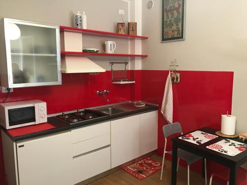 une petite cuisine avec un évier et un mur rouge dans l'établissement Ravenna Tourist Apartments, à Ravenne