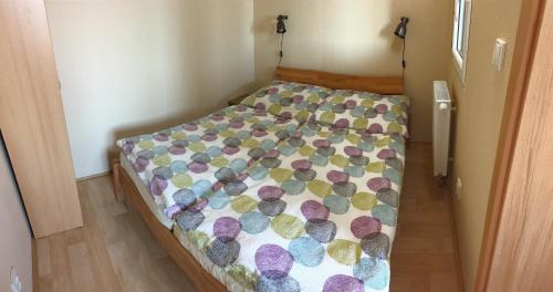 a small bedroom with a bed with a colorful comforter at PENZION HNAČOV in Zavlekov