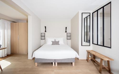 サントロペにあるStudios 10 & 11 BY HOTEL DES LICESのベッドルーム(白いベッド1台、木製ベンチ付)