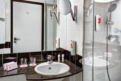 a bathroom with a sink and a shower at IntercityHotel Celle in Celle