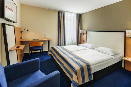 a hotel room with a bed and a chair at IntercityHotel Celle in Celle