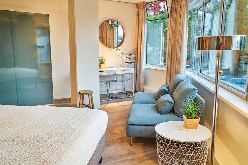 a bedroom with a bed and a couch and a table at Amrâth Apart-Hotel Schiphol Badhoevedorp in Badhoevedorp