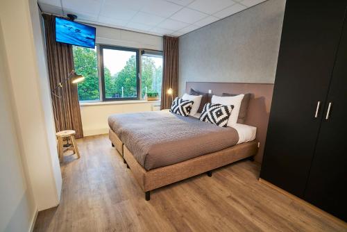 a bedroom with a bed with a television in it at Amrâth Apart-Hotel Schiphol Badhoevedorp in Badhoevedorp