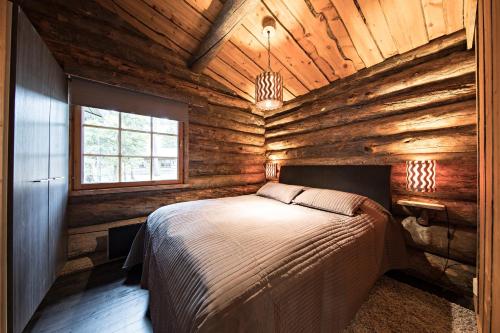 a bedroom with a bed in a wooden cabin at UnelmaKelo in Ruka