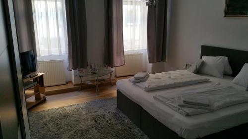 a bedroom with a bed and a table and windows at Appartement Hotel Marien-Hof in Vienna
