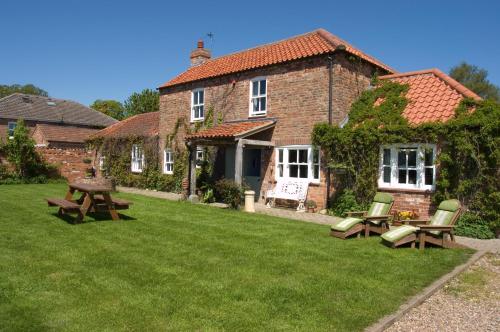 ein Haus mit einem Picknicktisch und Stühlen im Hof in der Unterkunft Jockhedge Holiday Cottages in Skegness