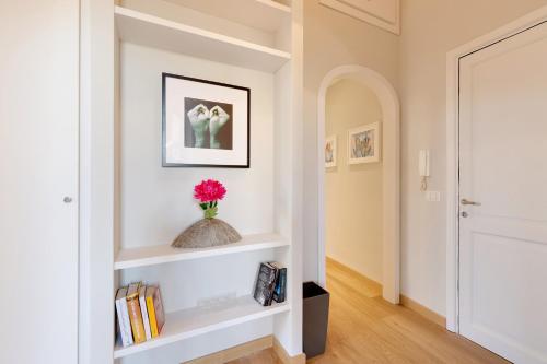 a hallway with white shelves and a vase with a pink flower at Rome as you feel - Grotta Pinta apartments in Rome
