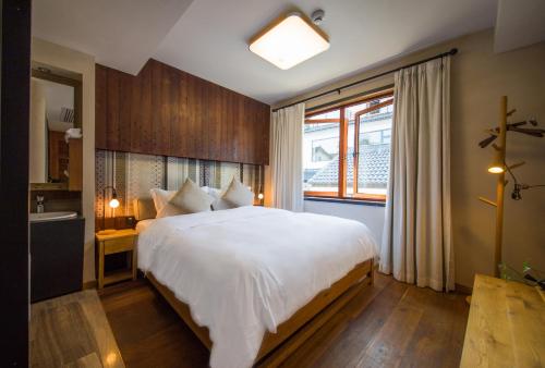 a bedroom with a large white bed and a window at Hangzhou Van Wind Inn in Hangzhou