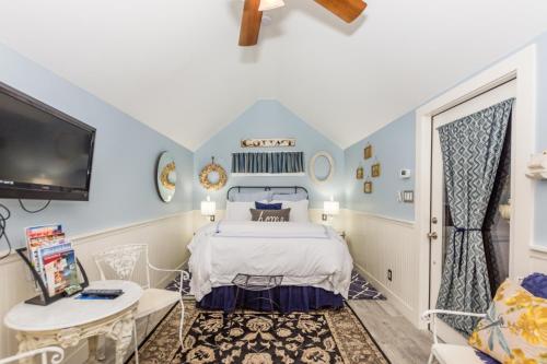 a blue and white bedroom with a bed and a tv at Agape Cottage in Fredericksburg