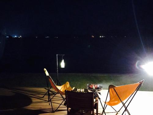 two chairs and a table on a patio at night at Holly Camp Airstream Villa Amami in Amami