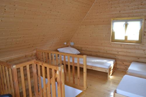 a log cabin with a bed and a window at Camping Szczecinek Domy Wypoczynkowe in Szczecinek
