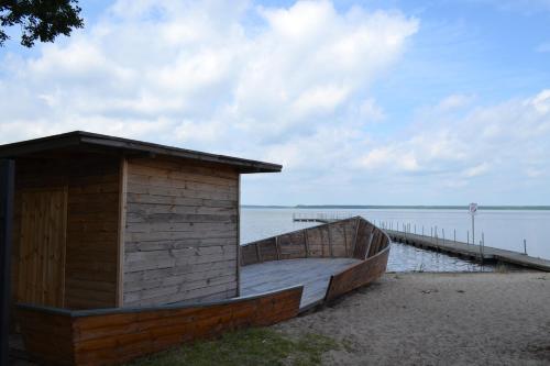 a wooden boat sitting on the beach next to a dock at Camping Szczecinek Domy Wypoczynkowe in Szczecinek